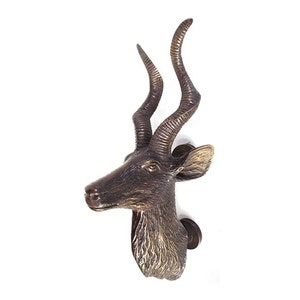 May include: A bronze door knocker shaped like an antelope head with long, curved horns.