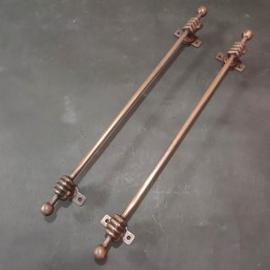 May include: Two antique-style copper curtain rods with decorative ball finials and a twisted rope design. The rods are approximately 30 inches long.