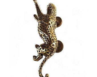 May include: A bronze-colored door handle shaped like a leopard climbing upwards. The handle has a textured surface with dark spots and two circular mounting plates. The leopard's tail curves gracefully, and its body is detailed.