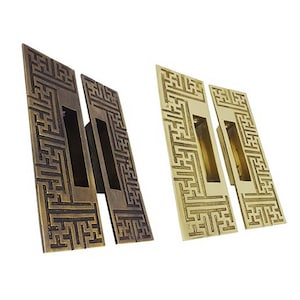 May include: Two pairs of decorative door pulls with a geometric pattern. One pair is a dark brass finish and the other is a lighter brass finish.