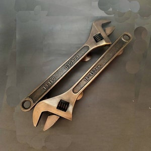 May include: Two antique-looking adjustable wrenches with the words "FORGED" and "STEEL" on the handles. The larger wrench is labeled "18"-24" 450mm".