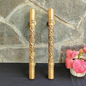 May include: Two gold door handles with intricate floral designs. The handles are made of brass and have a polished finish.