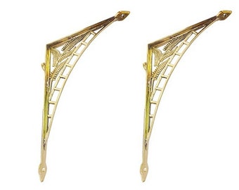 May include: Two gold metal shelf brackets with a decorative design. The brackets are curved and have a pointed end.