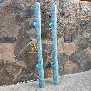 May include: Two turquoise blue metal door handles with intricate designs. The handles are cylindrical and have a textured surface. The handles are mounted on a stone wall.