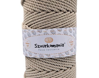 Könnte beinhalten: Ein beiger Baumwollseilgarn zum Häkeln. Das Garn ist zu einer Kugel gewickelt und hat ein Etikett mit der Aufschrift "Sznurkomania Pasja tworzenia" mit einem Häkelhaken-Symbol.