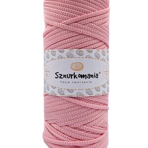 Könnte beinhalten: Ein rosa Baumwollgarn zum Häkeln oder Makramee. Das Garn ist zu einer Kugel gewickelt und hat ein Etikett mit der Aufschrift "Sznurkomania Pasja tworzenia".
