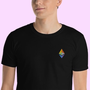 Puede incluir: Una camiseta negra con un logotipo de Ethereum bordado en arcoíris en la parte delantera.