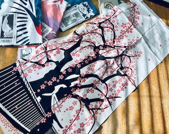 Può includere: Un asciugamano da tè in tessuto bianco con una silhouette nera di un ciliegio in fiore con fiori rosa. Il testo "ありがとう ございます" è scritto con inchiostro nero sull'asciugamano.