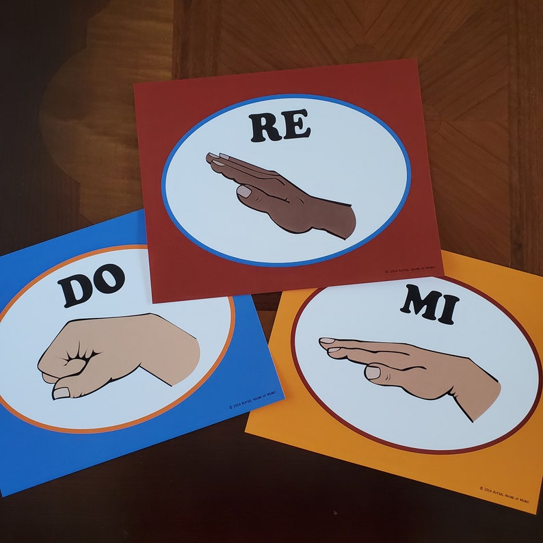 May include: Three colorful cards with blue, red, and orange backgrounds. Each card has a white circle with a hand sign and the word "DO", "RE", or "MI" in black text.