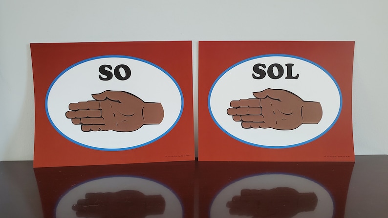 May include: Two red signs with white oval borders and blue outlines. Each sign features a brown hand with the words "SO" and "SOL" in black letters.