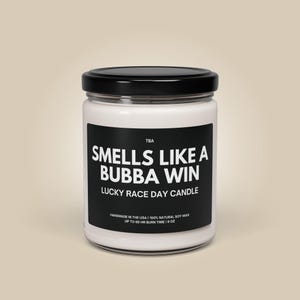 Könnte beinhalten: Ein weißes Kerzengefäß mit schwarzem Deckel und Etikett. Das Etikett lautet "TBA SMELLS LIKE A BUBBA WIN LUCKY RACE DAY CANDLE HANDMADE IN THE USA | 100% NATURAL SOY WAX UP TO 60 HR BURN TIME | 9 OZ"