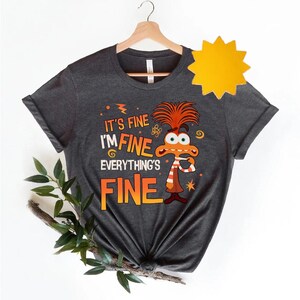 May include: A dark gray t-shirt with a cartoon character and the text "It's fine I'm fine Everything's fine".
