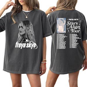 May include: Dark gray t-shirt featuring a portrait of Freya Skye with the text "freya skye" in white. The back of the shirt displays "FREYA SKYE Stars Align Tour" with a list of tour dates. A stylish and comfortable tee for fans.