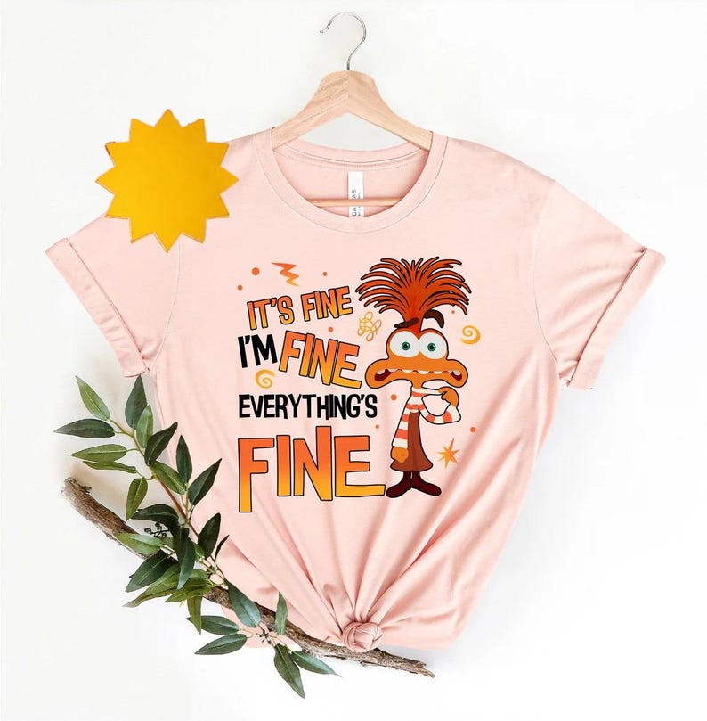 May include: Pink t-shirt with a cartoon character and the text "It's fine I'm fine Everything's fine".