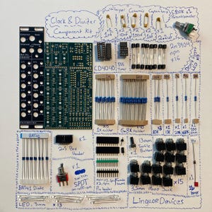 May include: A Clock & Divider Component Kit by Linguae Devices containing a black front panel, a green circuit board, various resistors, capacitors, 2n3904 transistors, a 555 timer, a CD4040 chip, a potentiometer, diodes, headers, a switch, and mono jacks.