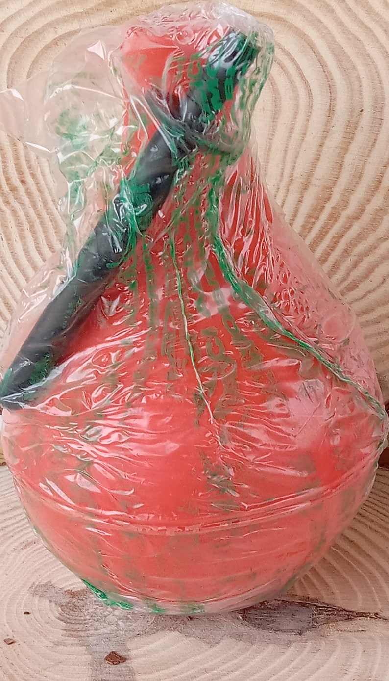May include: A red rubber bulb with a black plastic nozzle, wrapped in clear plastic with green lettering. The bulb is used for inflating items like balloons or sports balls.