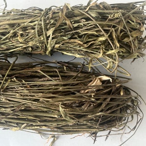 Könnte beinhalten: Zwei Bündel getrockneter, brauner und grüner Pflanzenstiele. Die Stiele sind miteinander verdreht und scheinen für Bastelarbeiten oder Blumenarrangements verwendet zu werden.