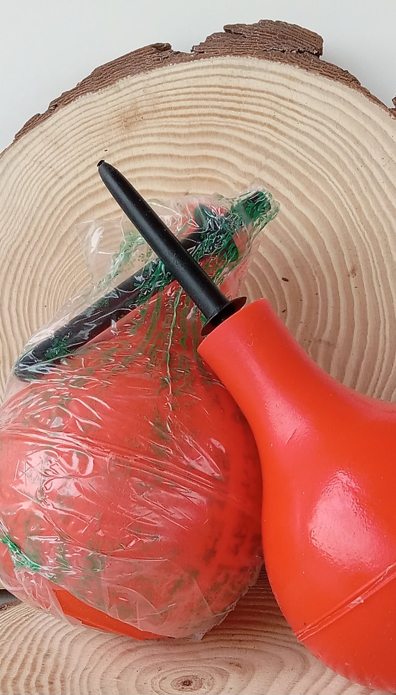 May include: Two red rubber enema bulbs, one with a black nozzle and the other wrapped in clear plastic with a green label.