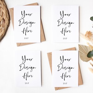 K&ouml;nnte beinhalten: Vier leere wei&szlig;e Karten mit braunen Umschl&auml;gen, jede Karte hat den Text "Your Design Here 5X7" darauf gedruckt. Die Karten sind quadratisch auf einer wei&szlig;en Oberfl&auml;che angeordnet. Im Hintergrund befinden sich getrocknete Blumen und gr&uuml;ne Bl&auml;tter.