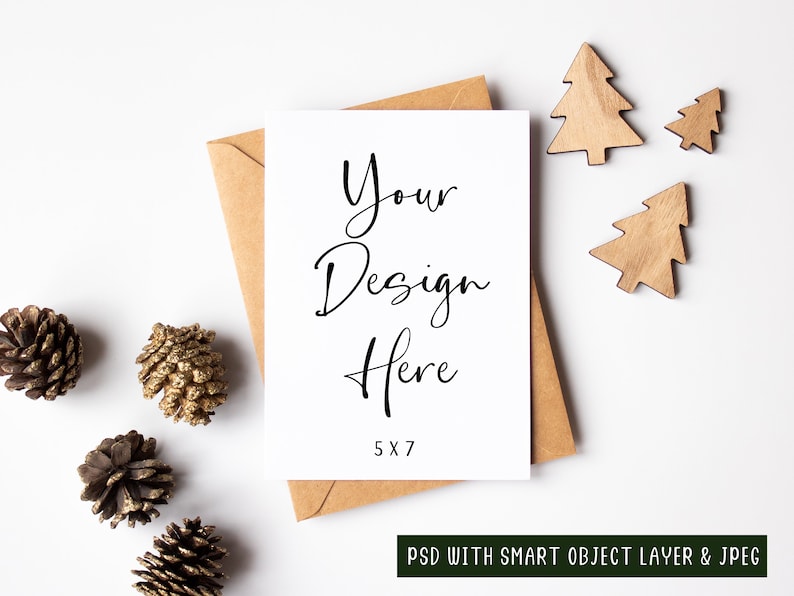 K&ouml;nnte beinhalten: Eine wei&szlig;e Karte mit dem Text "Your Design Here 5x7" auf einem braunen Umschlag mit Tannenzapfen und Holz-Weihnachtsb&auml;umen auf wei&szlig;em Hintergrund.