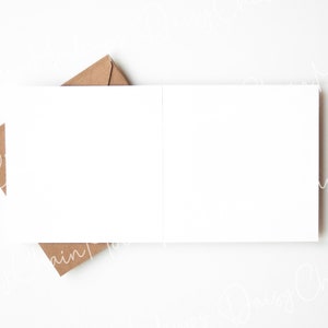May include: A blank white card with a brown envelope on top of it. The card is lying flat on a white surface.