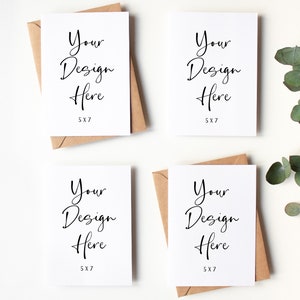 K&ouml;nnte beinhalten: Vier leere wei&szlig;e Gru&szlig;karten mit braunen Umschl&auml;gen. Jede Karte tr&auml;gt den Text "Your Design Here" und "5X7" gedruckt darauf. Die Karten sind quadratisch auf einer wei&szlig;en Oberfl&auml;che angeordnet. Ein Zweig Eukalyptus befindet sich in der oberen rechten Ecke des Bildes.