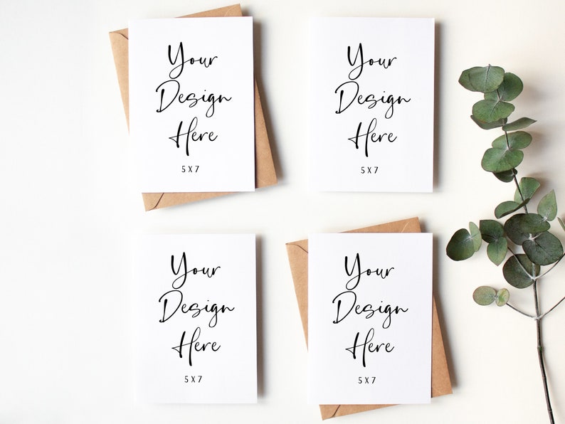 K&ouml;nnte beinhalten: Vier leere wei&szlig;e Gru&szlig;karten mit braunen Umschl&auml;gen. Jede Karte tr&auml;gt den Text "Your Design Here" und "5X7" gedruckt darauf. Die Karten sind quadratisch auf einer wei&szlig;en Oberfl&auml;che angeordnet. Ein Zweig Eukalyptus befindet sich in der oberen rechten Ecke des Bildes.