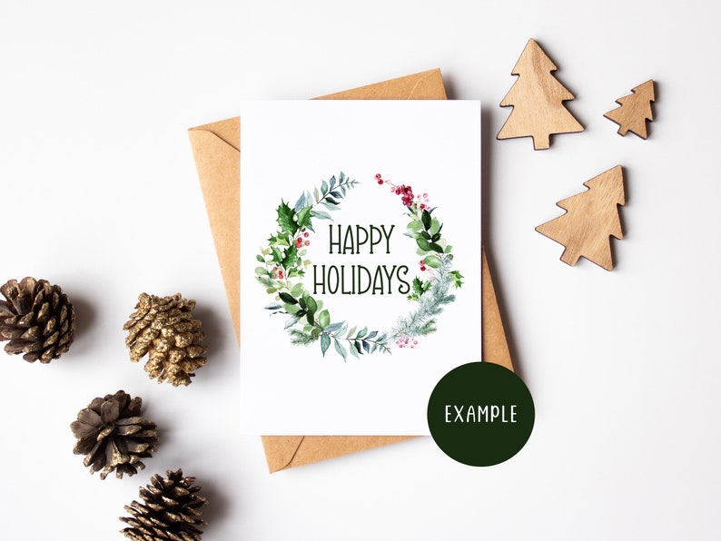 K&ouml;nnte beinhalten: Eine wei&szlig;e Karte mit einem gr&uuml;nen Aquarellkranz mit roten Beeren und dem Text "Happy Holidays". Die Karte ist von Tannenzapfen und Holz-Weihnachtsb&auml;umen auf wei&szlig;em Hintergrund umgeben.
