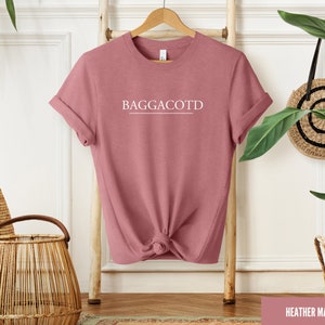 May include: Heather mauve t-shirt with the text "BAGGACOTD" printed in white on the front.