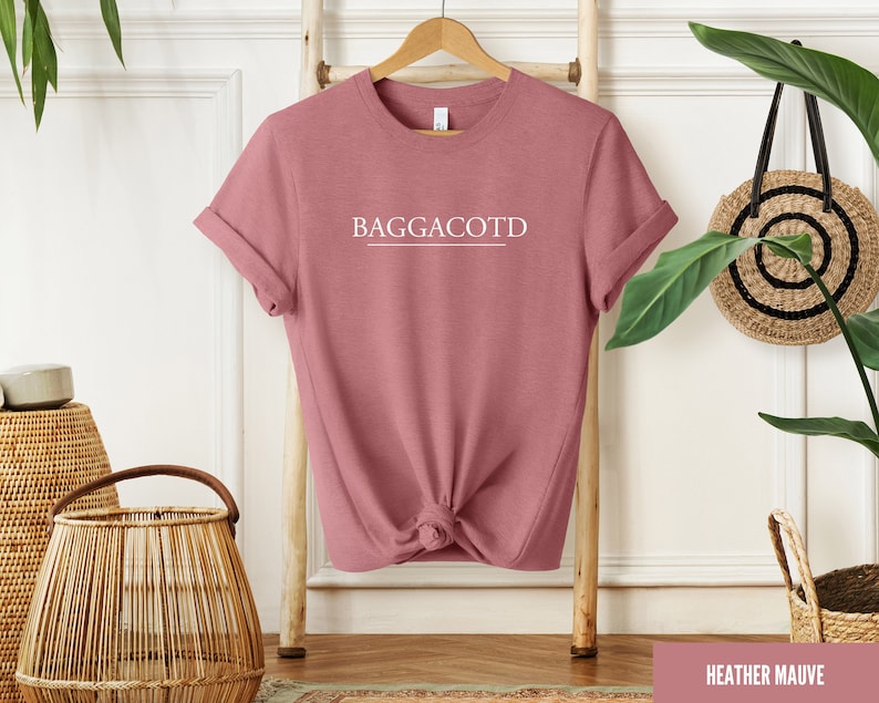 May include: Heather mauve t-shirt with the text "BAGGACOTD" printed in white on the front.