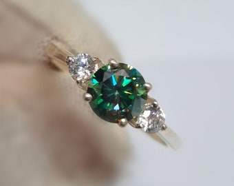 May include: A silver ring with a green and blue round gemstone surrounded by three smaller white gemstones.