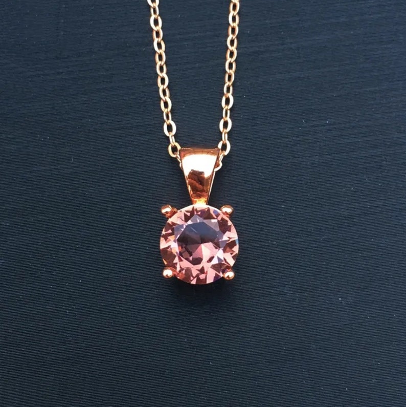 Puede incluir: Un collar de oro rosa con un colgante de piedra preciosa rosa.