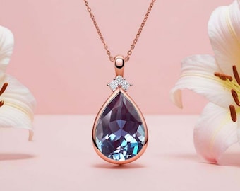 Op de afbeelding: Een ketting van roségoud met een traanvormige hanger met een blauwe en paarse edelsteen, omringd door kleinere heldere edelstenen.