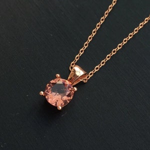 Puede incluir: Un collar de oro rosa con un colgante de piedra rosa.