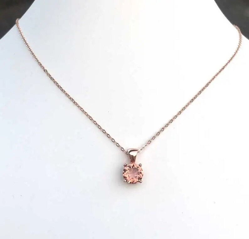 Puede incluir: Un delicado collar de cadena de oro rosa con un peque&ntilde;o colgante redondo de piedra preciosa de color melocot&oacute;n.