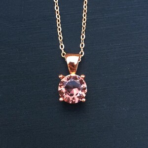 Puede incluir: Un collar de oro rosa con un colgante de piedra preciosa rosa.
