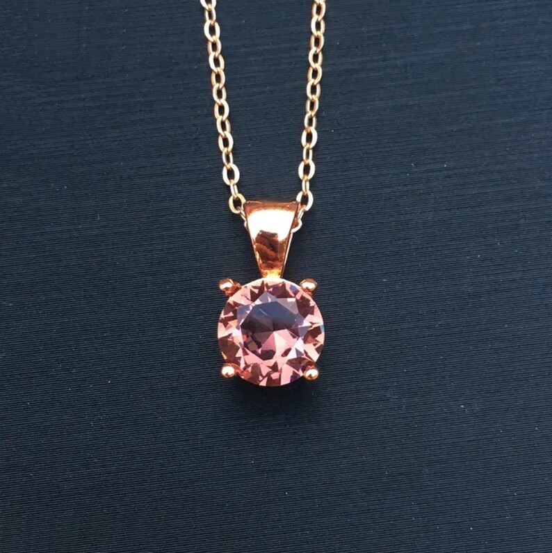 Puede incluir: Un collar de oro rosa con un colgante de piedra preciosa rosa.