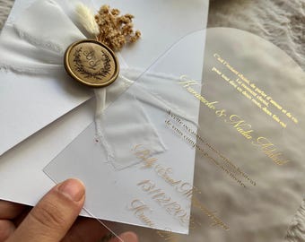 Invitación de boda con arco acrílico, sello de lacre, flores secas y sobre blanco. Elegante invitación en lámina dorada transparente para parejas modernas.