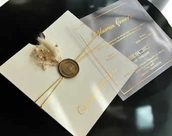 Op de afbeelding: Een witte huwelijksuitnodiging met gouden letters en een waszegel. De uitnodiging is voor een huwelijksceremonie en een receptie. De tekst op de uitnodiging luidt "Oglumuz Çınar'ın" en bevat de datum en tijd van het evenement.