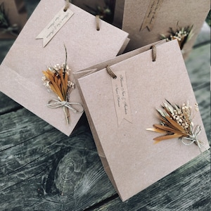 May include: Multiple brown paper gift bags with twine handles and small dried flower bouquets attached.