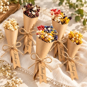 May include: Five small bouquets of dried flowers wrapped in brown paper cones. Each cone is tied with twine and features a rectangular tag with the text Thank you printed in black. The flowers include white, yellow, red, and blue varieties.