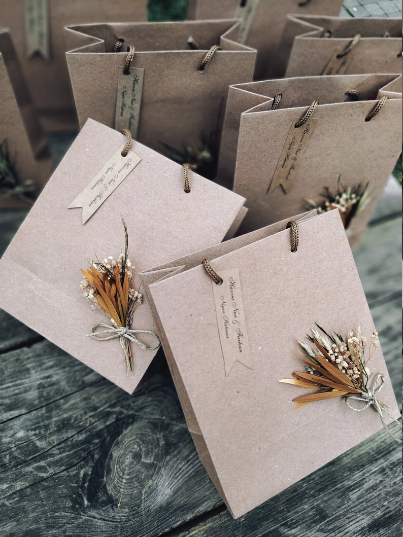 May include: Multiple brown paper gift bags with twine handles and small dried flower bouquets attached.