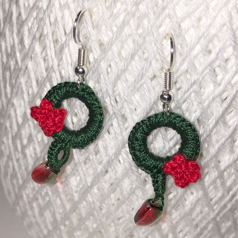 May include: Green and red crocheted wreath earrings with a red flower and a green and red bead dangle.