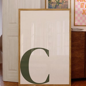 以下が含まれることがあります： 白い背景に大きな濃い緑色の文字「C」が描かれた、大きな額入りのプリント。 他に2つの額入りのプリントがあり、1つは風景と「PSALM 27」のテキスト、もう1つはピンクと白のチェック柄と「CONSIDER IT ALL JOY」のテキストです。