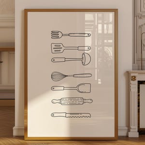 May include: A framed print featuring a collection of kitchen utensils in a minimalist style. The black line art includes a fork, spatula, whisk, rolling pin, and knife, all against a neutral background. The print is displayed in a room with a wooden floor.