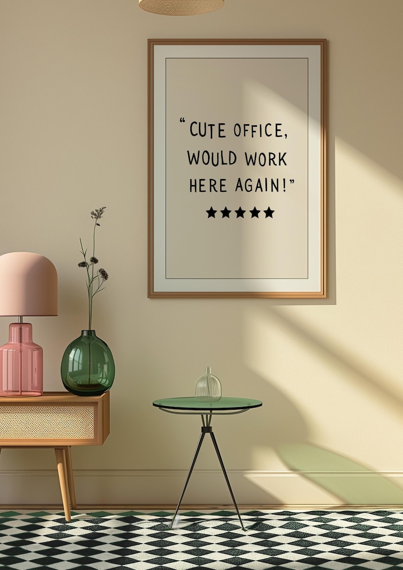 May include: A framed print with the text "CUTE OFFICE, WOULD WORK HERE AGAIN!" and five stars. The image also features a pink lamp, a green vase, a small side table, and a patterned rug.