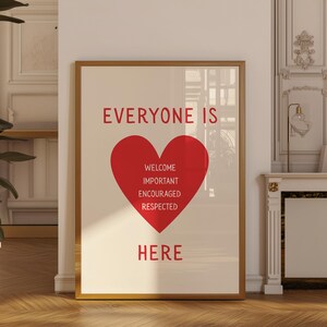 May include: A framed print with a gold-colored frame. The print features the words "EVERYONE IS" at the top, a large red heart in the center, and the word "HERE" at the bottom. Inside the heart are the words "WELCOME, IMPORTANT, ENCOURAGED, RESPECTED."