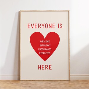 May include: A framed print with a cream background and red text. The text reads "EVERYONE IS HERE" with a red heart in the center containing the words "WELCOME IMPORTANT ENCOURAGED RESPECTED". The frame is a light wood color.