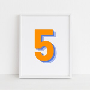 Peut inclure: Une impression encadrée blanche avec un grand chiffre cinq orange. Le chiffre a un contour bleu et une ombre.