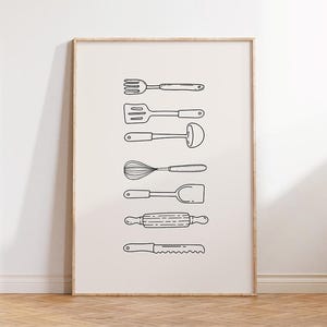 May include: A framed print featuring line drawings of various kitchen utensils, including a fork, spatula, ladle, whisk, turner, rolling pin, and bread knife. The utensils are black on a cream-colored background, creating a minimalist aesthetic.